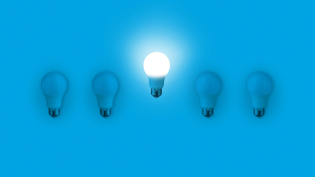 Blue light bulbs with glowing one different idea on blue background. minimal concept. top view. New Creative Idea